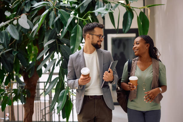 istock Happy colleagues communicating while going on coffee break in the office. 2154984348