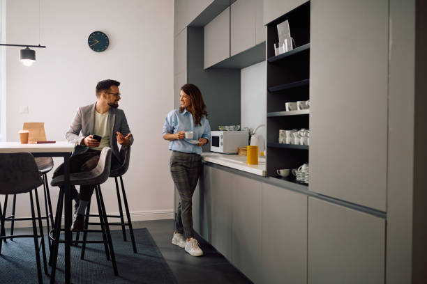 Happy coworkers communicating during coffee break in the office.