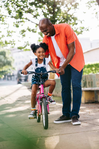 istock Happy father teaching daughter to ride bicycle in the park 2154986937