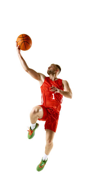 Young man in red basketball jersey and shorts, leaping in motion high for powerful dunk against white studio background. Young man in red basketball jersey and shorts, leaping in motion high for powerful dunk against white studio background. Concept of professional sport, games, healthy lifestyle, tournament, action. Ad basketball player stock pictures, royalty-free photos & images