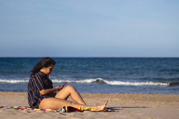 istock Girl sitting on the beach watching the mobile 2154990577
