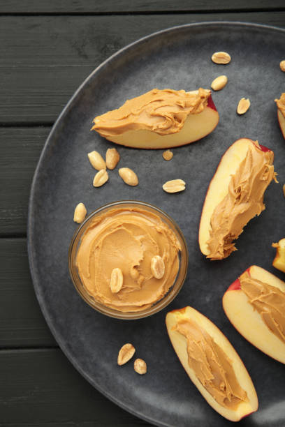 istock Slices of fresh apple with peanut butter and nuts on dark background. 2154990597