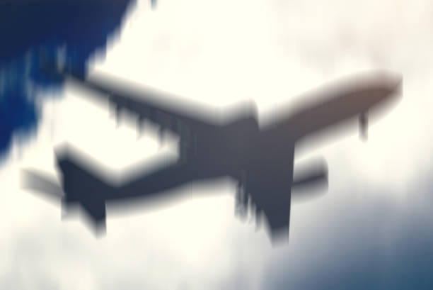 A blurry silhouette of a jet airliner is seen in mid-air, suggesting it is experiencing turbulence. The sky in the background appears overcast, adding to the intensity of the scene. Deliberately blurry
