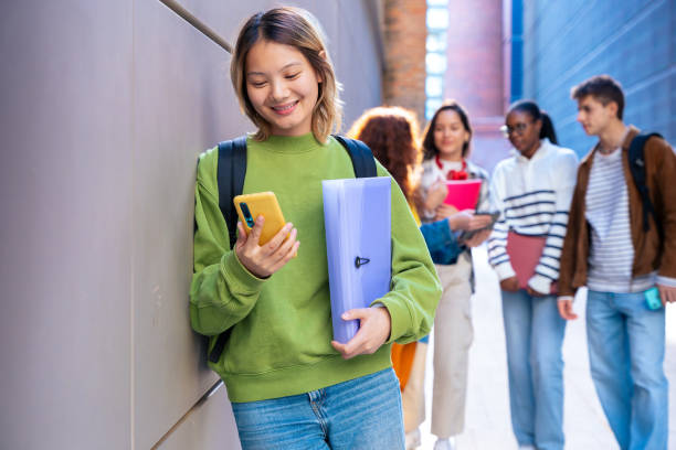 istock Happy young chinese woman browsing the internet using mobile device outdoors. 2155002304