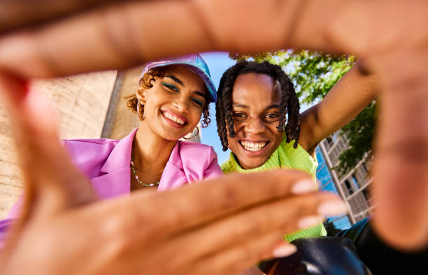 istock Two Gen Z adults smiling and looking through a hand frame gesture outdoors in an urban environment. Low angle shot. 2155004425