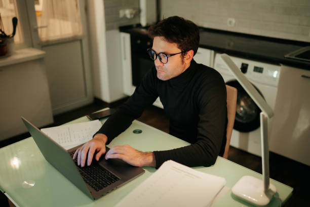 istock Late Night Work Session Young Male Student Browsing on Laptop at Home 2155011095