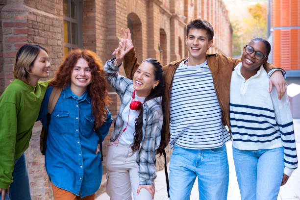 istock Multiethnic group of happy and smiling students with notebooks in hand walking . 2155015951