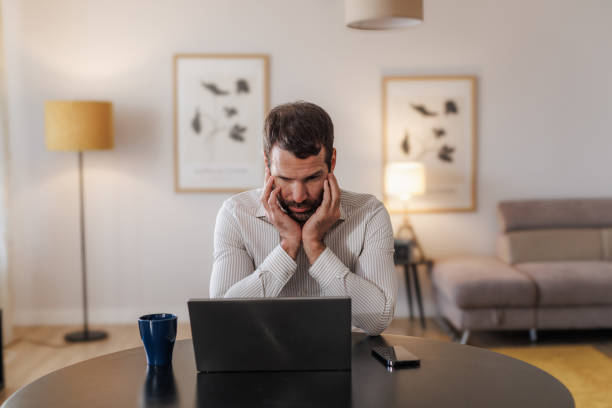 istock Worried man working on laptop at home office 2155020243