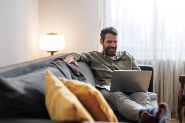 istock Man relaxing on the couch and using a laptop at home 2155020309