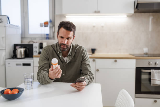 istock Man checking medication instructions on smart phone in kitchen 2155020354