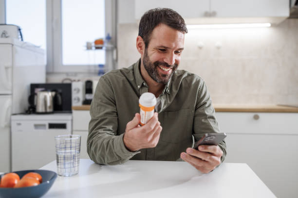 istock Smiling man checking medication instructions on smart phone in kitchen 2155020374
