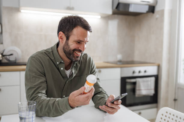 istock Man reading medication instructions from a smart phone in the kitchen 2155020393