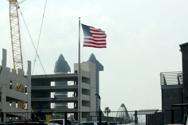 US Flag waves in front of two Starships at the SpaceX assembly facility in Boca Chica, Texas