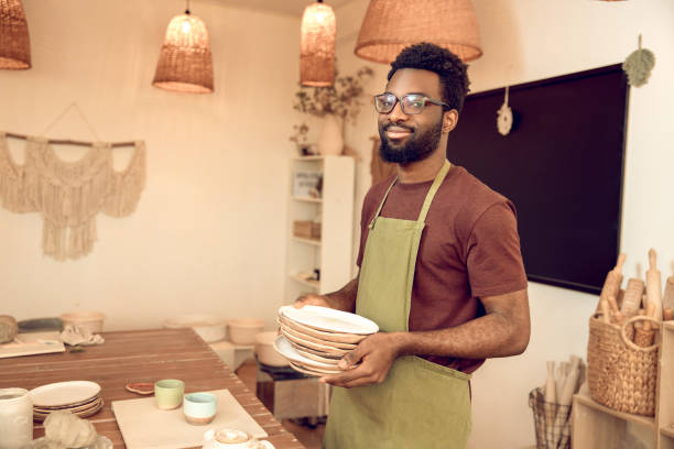 istock Man in apron standing with ceramic plates in hands 2155026024