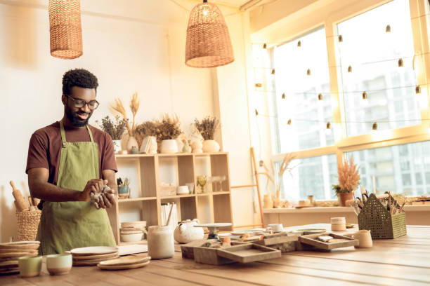 istock Dark-skinned sculptor molding clay in his hands 2155026033