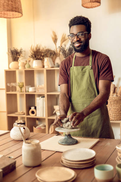 istock Dark-skinned sculptor molding clay in his hands 2155026040