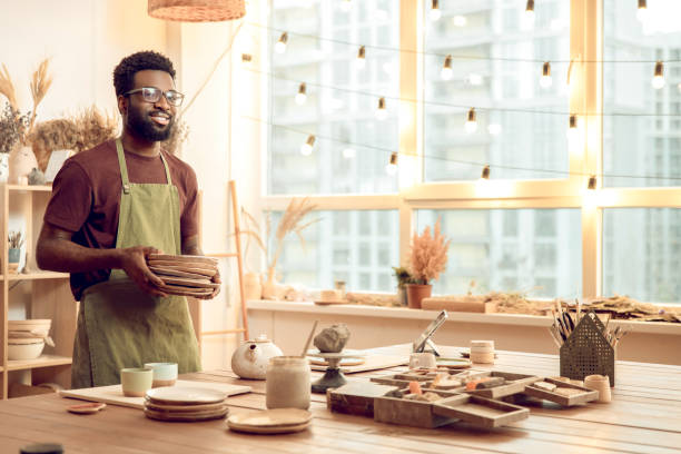 istock Dark-skinned man in eyeglasses working with pottery in his workshop 2155026048
