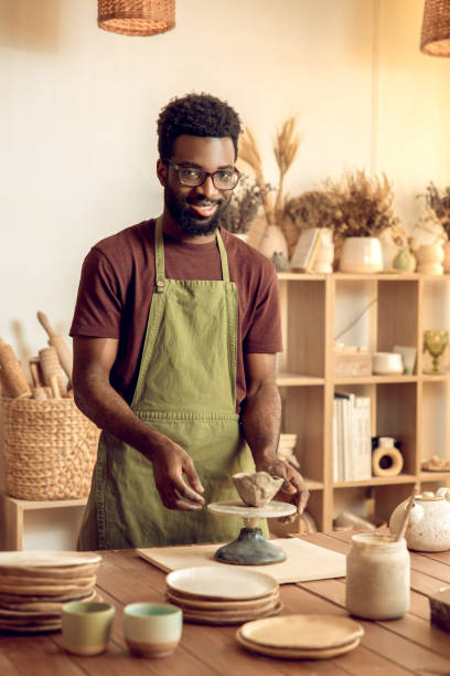 istock Dark-skinned sculptor molding clay in his hands 2155026055