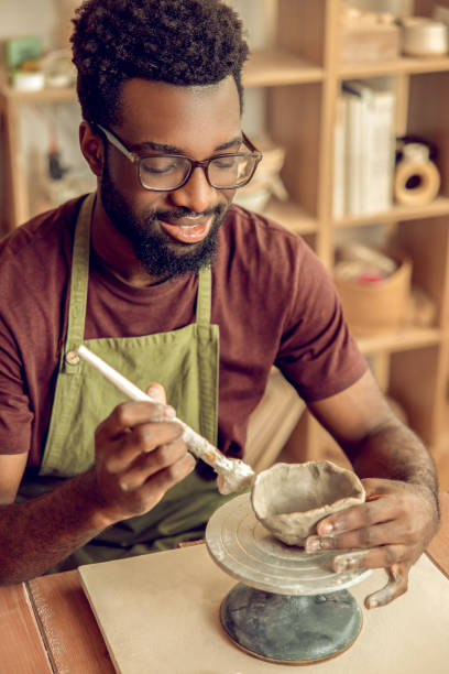 istock Male sculptor working on a new clay mug in his office 2155026719