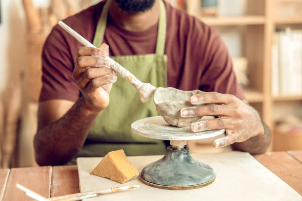 istock Male sculptor working on a new clay mug in his office 2155026725