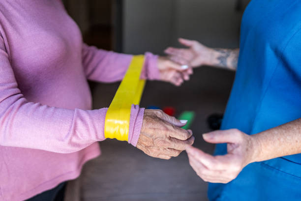 istock Senior woman doing exercises with rubber band during house call 2155027302