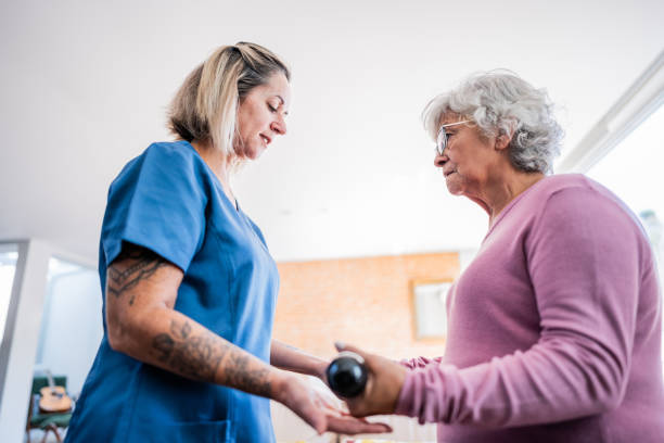 istock Physical therapist helping senior woman exercising with weights 2155027625