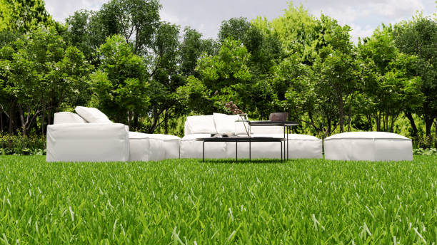 A single lounge chair sits on a grassy hill, overlooking a scenic view of green fields and trees under a clear blue sky. The setting exudes tranquility, inviting relaxation amidst nature.