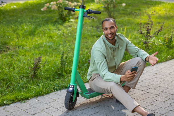 istock Cheerful man with e-scooter using mobile plication on his smartphone during walking in city street 2155030233