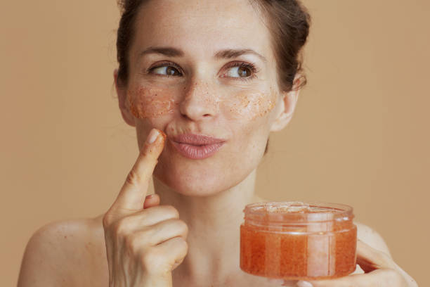 istock smiling young female with face scrub on beige background 2155031762