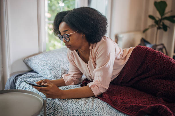istock Person lounging on bed with smartphone 2155035189