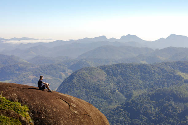 istock Man Sitting on Rock, Contemplating Nature and Reflecting in Thought. 2155038490