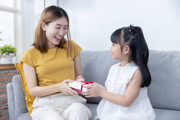 istock Little Girl Give a Gift Box  to Her Surprised Mother 2155040468