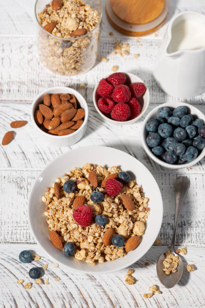 istock homemade granola with nuts and fresh berries on white table, vertical top view 2155040982