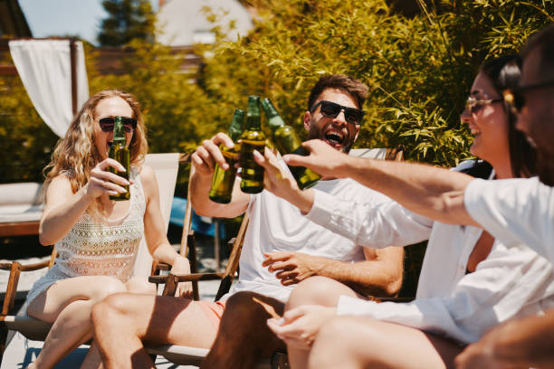 istock Young group of people drinking beer and having fun by the pool 2155043084