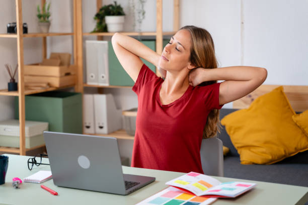 istock Young woman taking a break from work, stretching her neck in a cozy office environment 2155047160