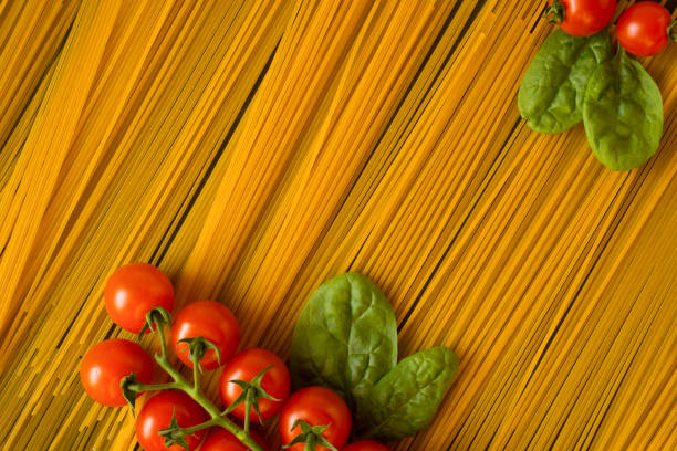 spaghetti with vegetables on a dark background, cherry tomato, spinach. flat lay