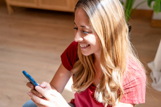istock Joyful young woman using her phone in a well-lit room 2155047807