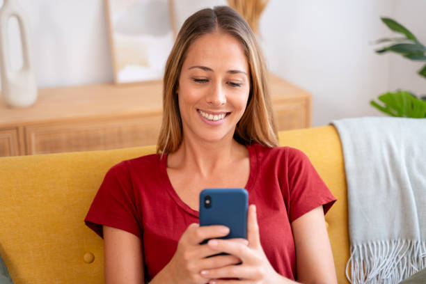 istock Cheerful young woman enjoys her time on a couch, browsing through her phone 2155048556