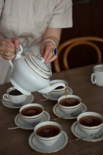 istock Woman Pouring Tea Into Cups on Table 2155050143