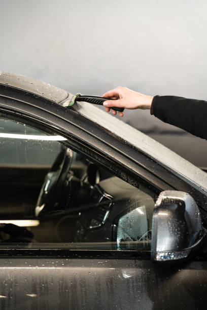 istock Removing water from windscreen using scraper at car wash service. Process of manual washing car. 2155050260