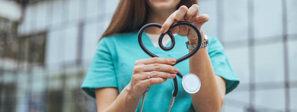 istock Caucasian Nurse Forms Heart with Stethoscope Outdoors 2155050540