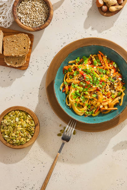 istock Delicious Udon Noodles with Vegetables and Sesame Seeds on Rustic Table Setting 2155051197