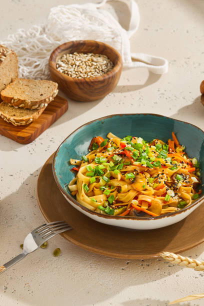 istock Delicious Udon Noodles with Fresh Vegetables and Sesame Seeds on Rustic Table 2155051199