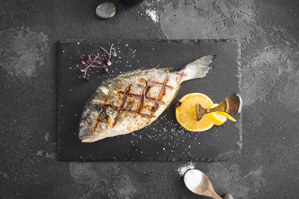 istock Elevated View of Grilled Fish on Slate Plate 2155051486