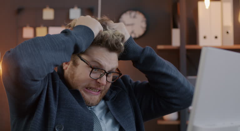 Loop of mad businessperson pulling hair and screaming expressing negative emotion looking at computer screen in office