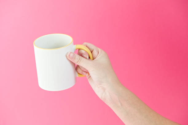 istock Woman's hamd holding coffee, tea ceramic cup on a pink background. 2155054951