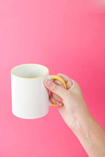 istock Woman's hamd holding coffee, tea ceramic cup on a pink background. 2155054963
