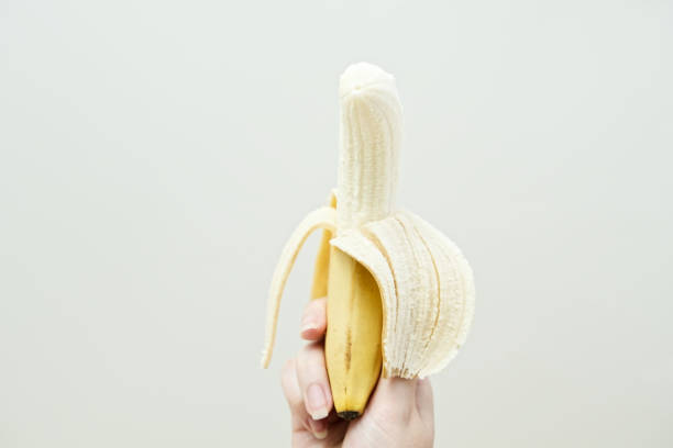 istock Woman's hand holding peeled banana fruit. 2155055075