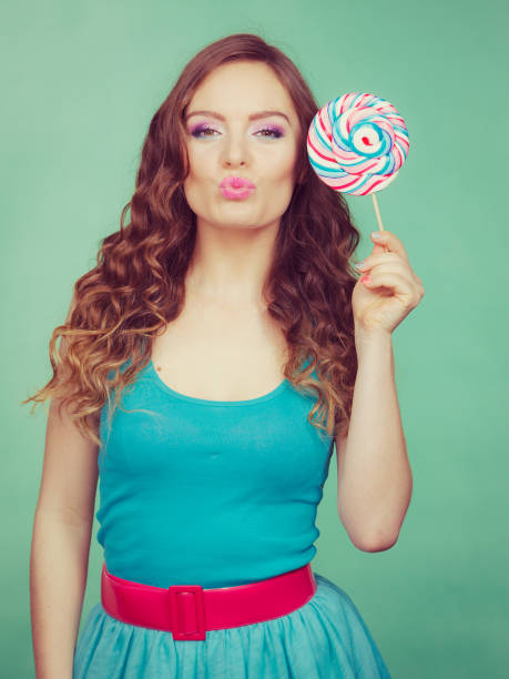 istock Smiling girl with lollipop candy on teal 2155055118