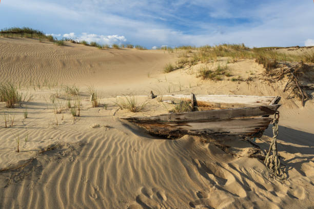 Beautiful Grey Dunes, Dead Dunes at the Curonian Spit in Nida, Neringa, Lithuania. The wreck of a fishing boat in the foreground